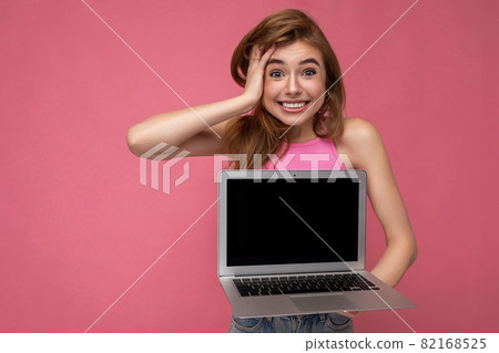 Shot of charming amazed surprised young woman holding computer laptop with empty monitor display 82168525