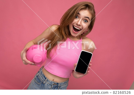 Surprised beautiful happy young woman wearing casual outfit isolated over background with empty 82168526