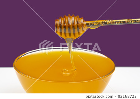 fresh honey drips from a spoon into a plate. organic vitamin health food 82168722