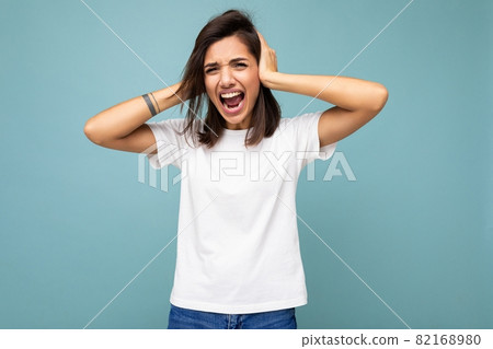 Portrait of emotional young attractive brunette woman with sincere emotions wearing casual white t 82168980