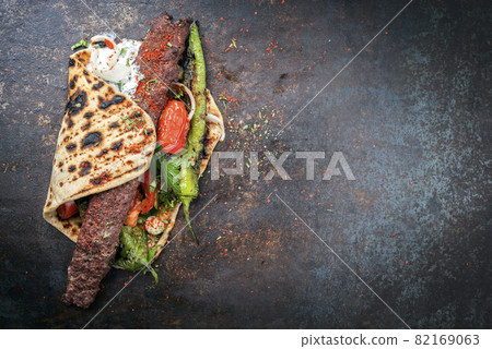 Traditional adana kebap on a skewer with tomato and yogurt 82169063