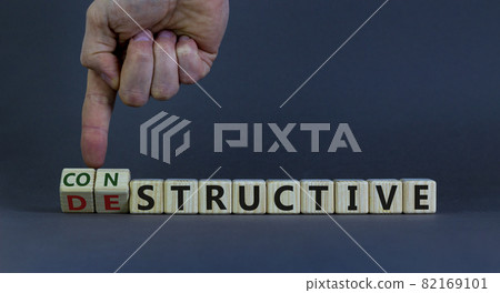 Destructive or constructive symbol. Male hand turns cubes and changes the word 'destructive' to 'constructive'. Business and constructive concept. Beautiful grey background, copy space. 82169101