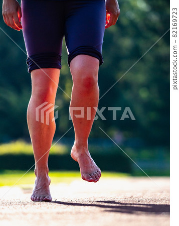 Solid bare feet of a hard training woman runs along running track 82169723
