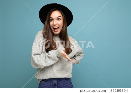 Photo of beautiful brunette happy joyful young woman directing finger to the side with copy space 82169864