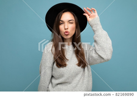 Young beautiful brunet woman. Trendy lady in casual grey sweater and stylish black hat. Positive Young beautiful brunet woman. Trendy lady in casual grey sweater and stylish black hat. Positive 82169890