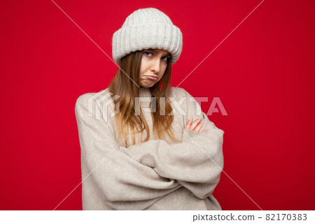 Photo shot of attractive touchy unhappy young dark blonde woman standing isolated over red Photo shot of attractive touchy unhappy young dark blonde woman standing isolated over red 82170383