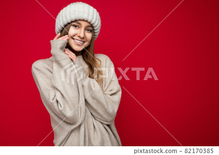 Shot of attractive happy smiling young dark blonde woman standing isolated over red background wall Shot of attractive happy smiling young dark blonde woman standing isolated over red background wall 82170385