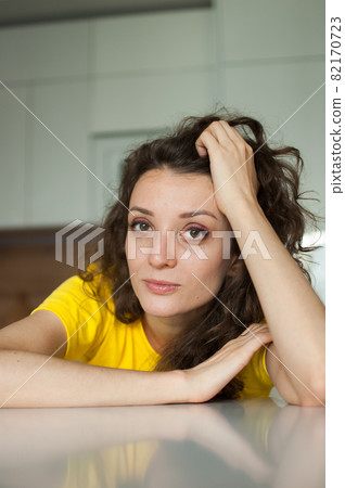 Beautiful curly girl in yellow t-shirt is looking at the camera at home in her apartment, posing with smile, happy people concept Beautiful curly girl in yellow t-shirt is looking at the camera at home in her apartment, posing with smile, happy people concept 82170723