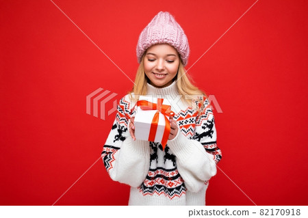 Photo shot of beautiful happy smiling young blonde woman isolated over red background wall wearing 82170918