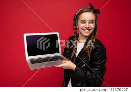 Photo of beautiful happy smiling girl with brunet pigtails holding computer laptop wearing black Photo of beautiful happy smiling girl with brunet pigtails holding computer laptop wearing black 82170997