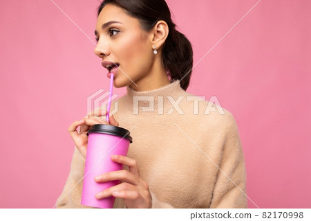 Charming young happy brunette woman wearing stylish clothes isolated over colourful background wall 82170998