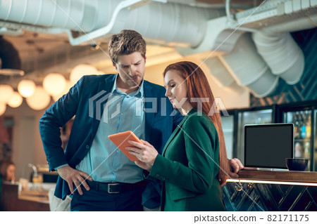 Woman showing tablet to serious man Woman showing tablet to serious man 82171175