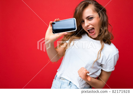 Crazy smiling young blonde woman good looking wearing white t-shirt standing isolated on red Crazy smiling young blonde woman good looking wearing white t-shirt standing isolated on red 82171928