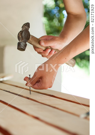 Female hands are using claw hammer and nail for making wooden bench, gender equality, feminism, do it yourself concepts. Female hands are using claw hammer and nail for making wooden bench, gender equality, feminism, do it yourself concepts. 82171929