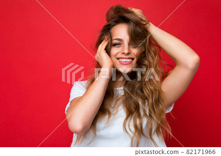 Young beautiful blond woman wearing white t-shirt looking at camera. Positive female shows facial Young beautiful blond woman wearing white t-shirt looking at camera. Positive female shows facial 82171966
