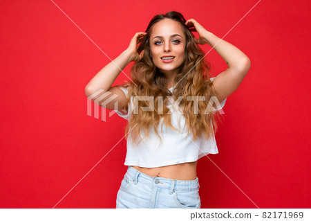 Young beautiful blond woman wearing white t-shirt looking at camera. Positive female shows facial Young beautiful blond woman wearing white t-shirt looking at camera. Positive female shows facial 82171969