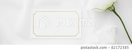 Wedding invitation or gift card and white rose flowers on silk fabric as bridal flatlay background, blank paper and holiday branding, flat lay design 82172385