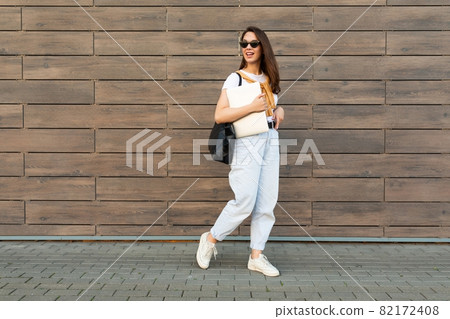 Full length photo shot of young charming beautifyl brunet woman going in the street near brown wall Full length photo shot of young charming beautifyl brunet woman going in the street near brown wall 82172408