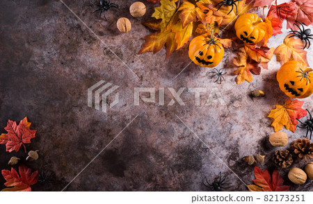 Halloween decorations made from pumpkin, paper bats and black spider on dark stone background. Flat lay, top view with copy space for text. 82173251