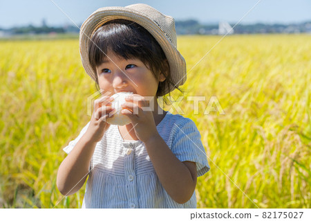 A girl chewing onigiri 82175027