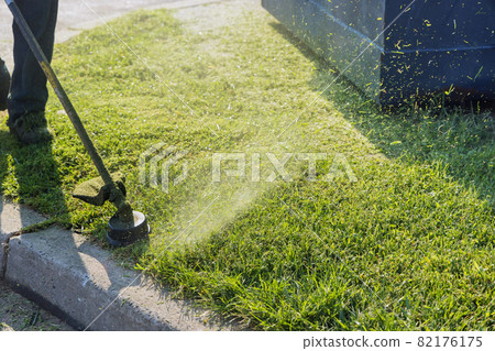 Close up on string trimmer head weed cutter brushcutter working in the yard cutting grass in garden Close up on string trimmer head weed cutter brushcutter working in the yard cutting grass in garden 82176175