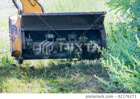 Wheeled tractor lawn mower with a external detachable mounted mower equipment driving on roadside of a suburban highway 82176271