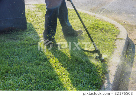 The gardener man mows the grass with a hand lawn mower. The gardener man mows the grass with a hand lawn mower. 82176508