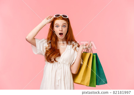 Waist-up portrait impressed, excited and surprised ginger girl, foxy curly hair, take-off sunglasses, seeing amazing discounts in store, hurry up to buy something, holding bags with shopping goods Waist-up portrait impressed, excited and surprised ginger girl, foxy curly hair, take-off sunglasses, seeing amazing discounts in store, hurry up to buy something, holding bags with shopping goods 82181997