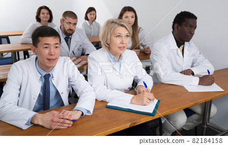 people attentively listening and making notes people attentively listening and making notes 82184158