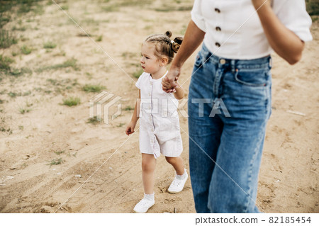 Mom and her little daughter are walking, holding hands, spending time together Mom and her little daughter are walking, holding hands, spending time together 82185454