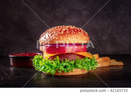 Burger on black, with French fries and ketchup. Beef patty steak with lettuce Burger on black, with French fries and ketchup. Beef patty steak with lettuce 82185735