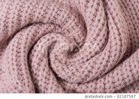 knitted fabric of large knit, pink pastel color, twisted in a circle, like a snail knitted fabric of large knit, pink pastel color, twisted in a circle, like a snail 82187587