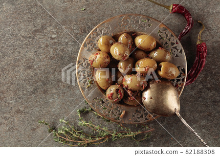 Spicy green olives in olive oil on a old stone table. 82188308