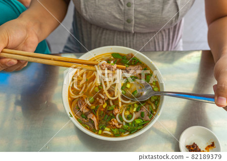 Young woman eating Bun Bo Hue, popular and delicious Vietnamese food 82189379