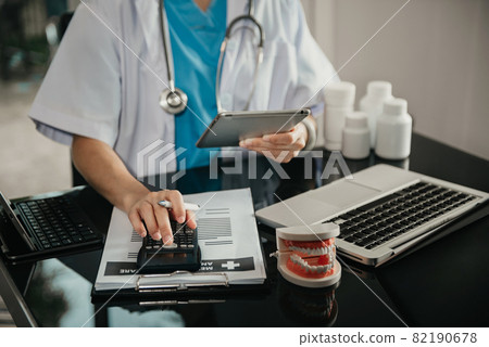Doctor physician with stethoscope calculate medical fee costs & revenue. practitioner use calculator at Clinic. 82190678