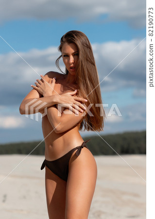 Alluring woman covering breast on beach 82190773