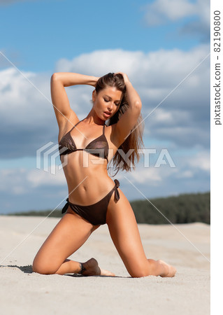 Graceful woman in bikini on sandy beach Graceful woman in bikini on sandy beach 82190800