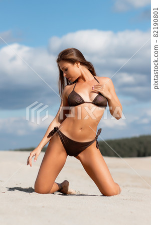 Graceful woman in bikini on sandy beach Graceful woman in bikini on sandy beach 82190801