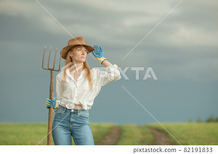 Country woman in field with pitchfork Country woman in field with pitchfork 82191833
