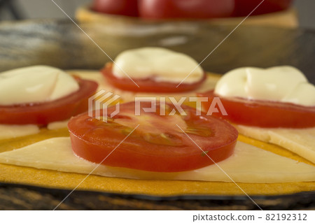 Slices of cherry tomatoes on slices of cheese on a tortilla 82192312