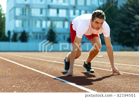 One young sportive man, male athlete, runner practicing alone before race at public stadium, sport court or running track, outdoors. Professional sport games. One young sportive man, male athlete, runner practicing alone before race at public stadium, sport court or running track, outdoors. Professional sport games. 82194501