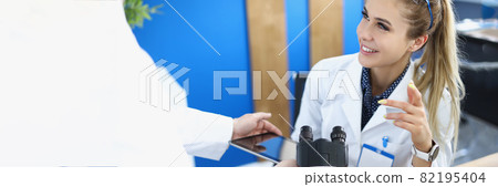 Assistant showing woman chemist information on digital tablet screen in laboratory 82195404