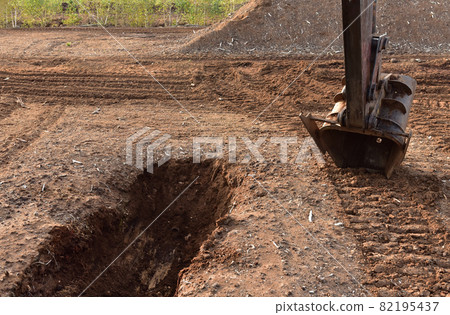 Excavator digging drainage ditch in peat extraction site.  82195437