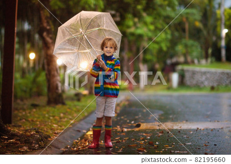 Child playing in autumn rain. Kid with umbrella. Child playing in autumn rain. Kid with umbrella. 82195660