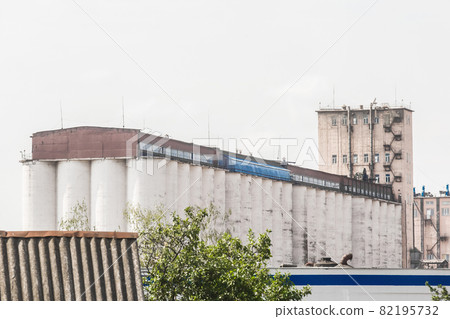 Industrial enterprise in the city with large storage tanks towers for storage of grain, food or chemical products Industrial enterprise in the city with large storage tanks towers for storage of grain, food or chemical products 82195732