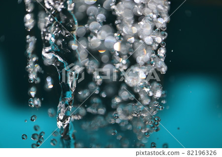A thick twisted streak, water droplets of various shapes, and a blurry white glow in the shower water of the tap taken with a macro lens. 82196326
