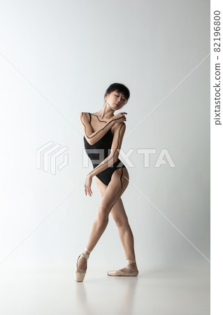 Young and graceful ballet dancer, ballerina dancing isolated on light gray studio background. Art, motion, action, flexibility, inspiration concept. Young and graceful ballet dancer, ballerina dancing isolated on light gray studio background. Art, motion, action, flexibility, inspiration concept. 82196800