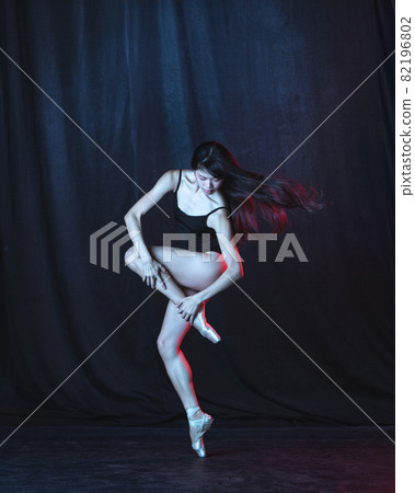 Young and graceful female ballet dancer in motion isolated on dark background in neon light. Art, motion, action, flexibility, inspiration concept. Young and graceful female ballet dancer in motion isolated on dark background in neon light. Art, motion, action, flexibility, inspiration concept. 82196802