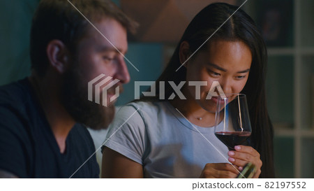 Diverse couple drinking wine in living room Diverse couple drinking wine in living room 82197552