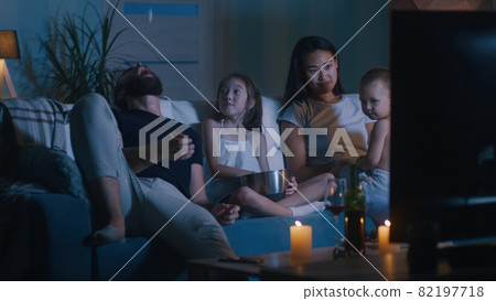 Diverse family watching movie in dark living room 82197718